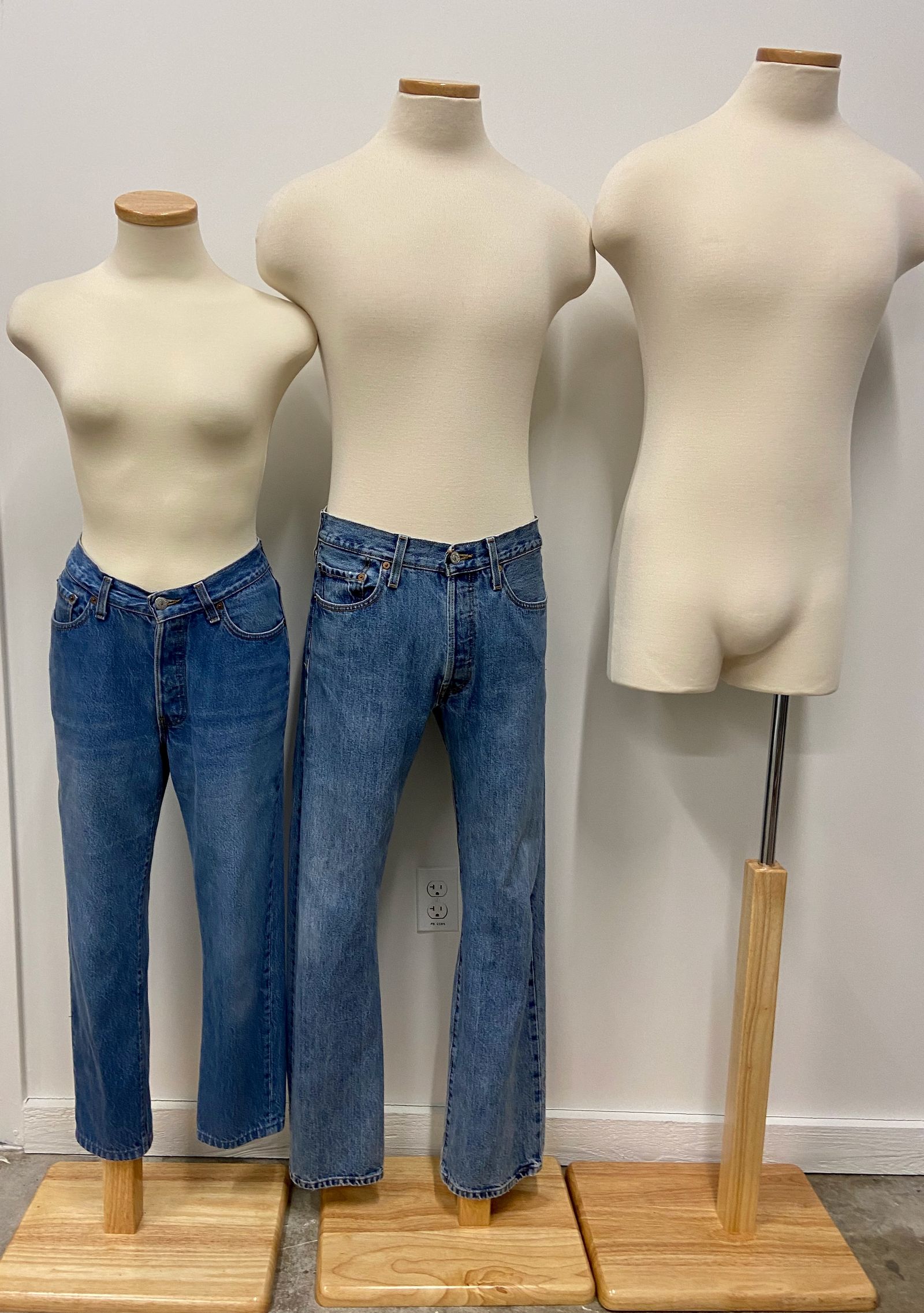 Three mannequins, two wearing blue jeans.