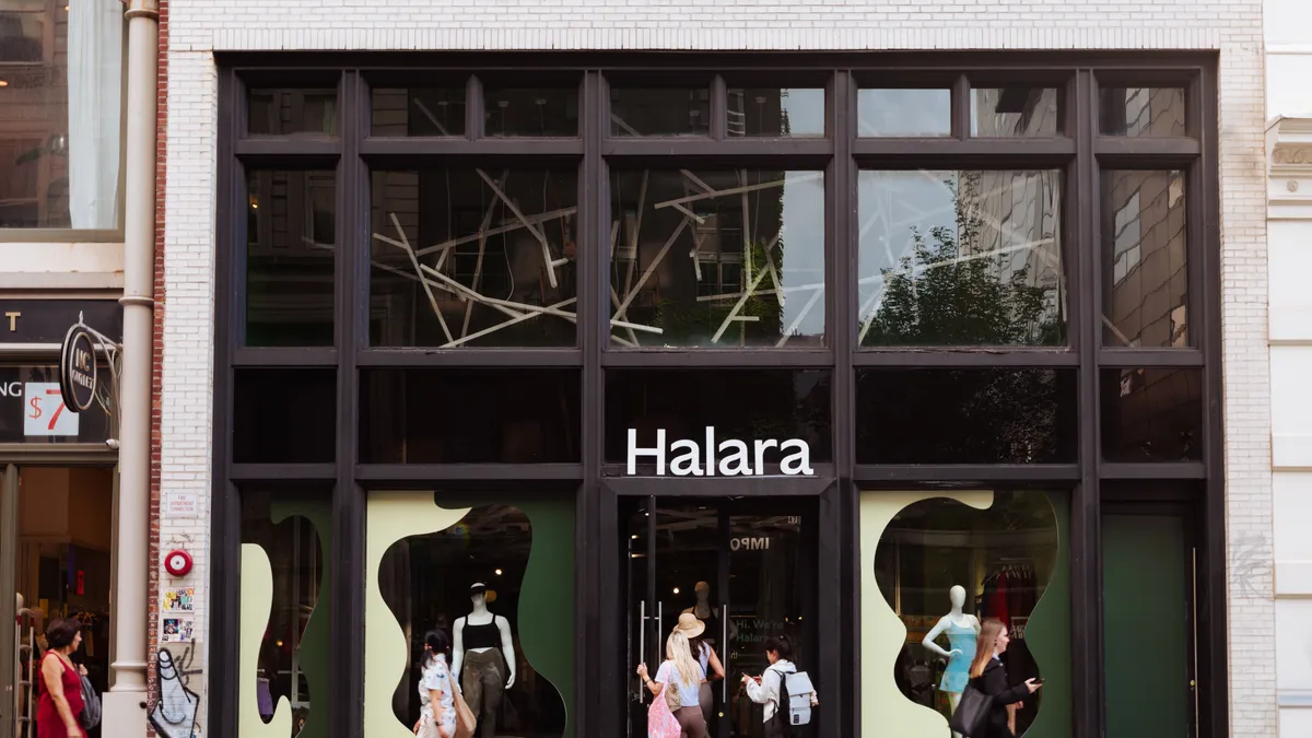 Shoppers walk by a black storefront with the name "Halara" on it.