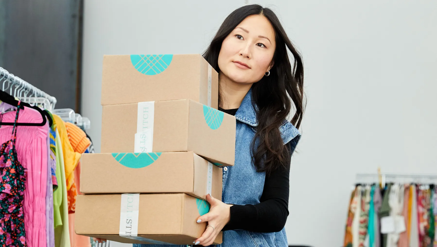 A person with long hair carries a stack of boxes.