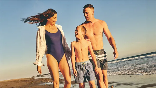 Three people walking along a beach wearing Fair Harbor apparel.