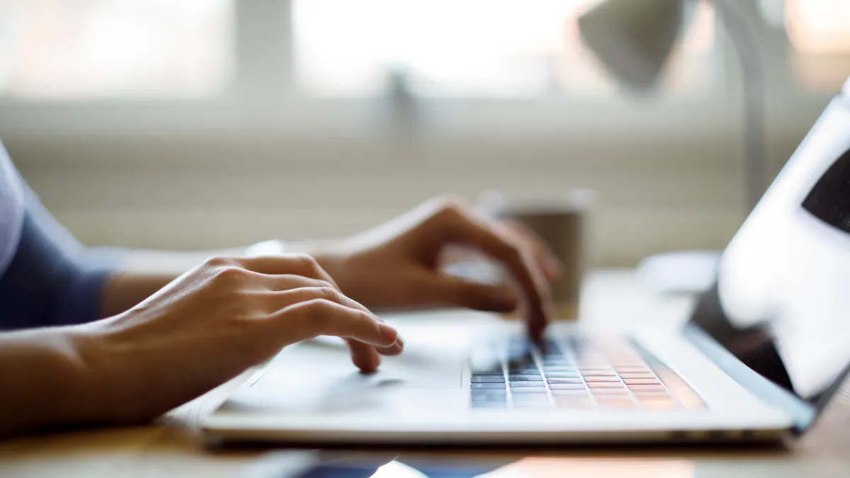 Close up of person's hands typing on a laptop