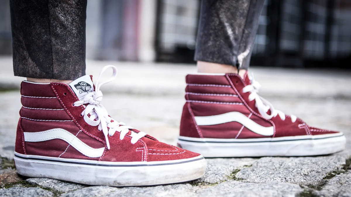 A close up of a person's shoes, high top vans classics in maroon.